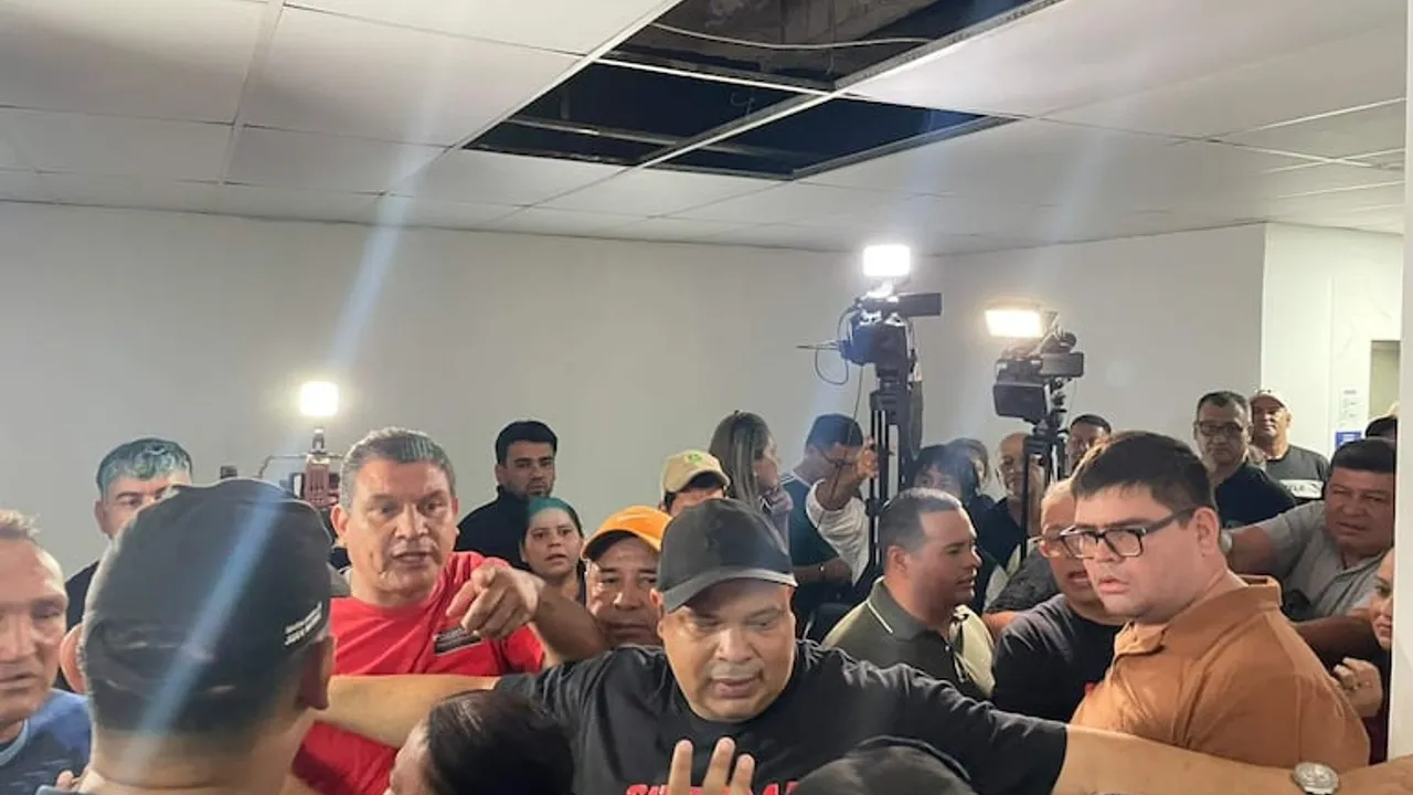 Grupo de personas y dirigentes gremiales discuten en un pasillo abarrotado frente a cámaras de televisión.