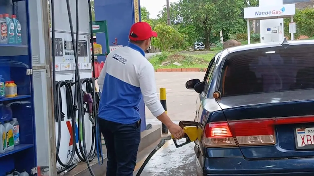 Un playero carga carburante en el tanque de un vehículo estacionado junto al surtidor de una estación.
