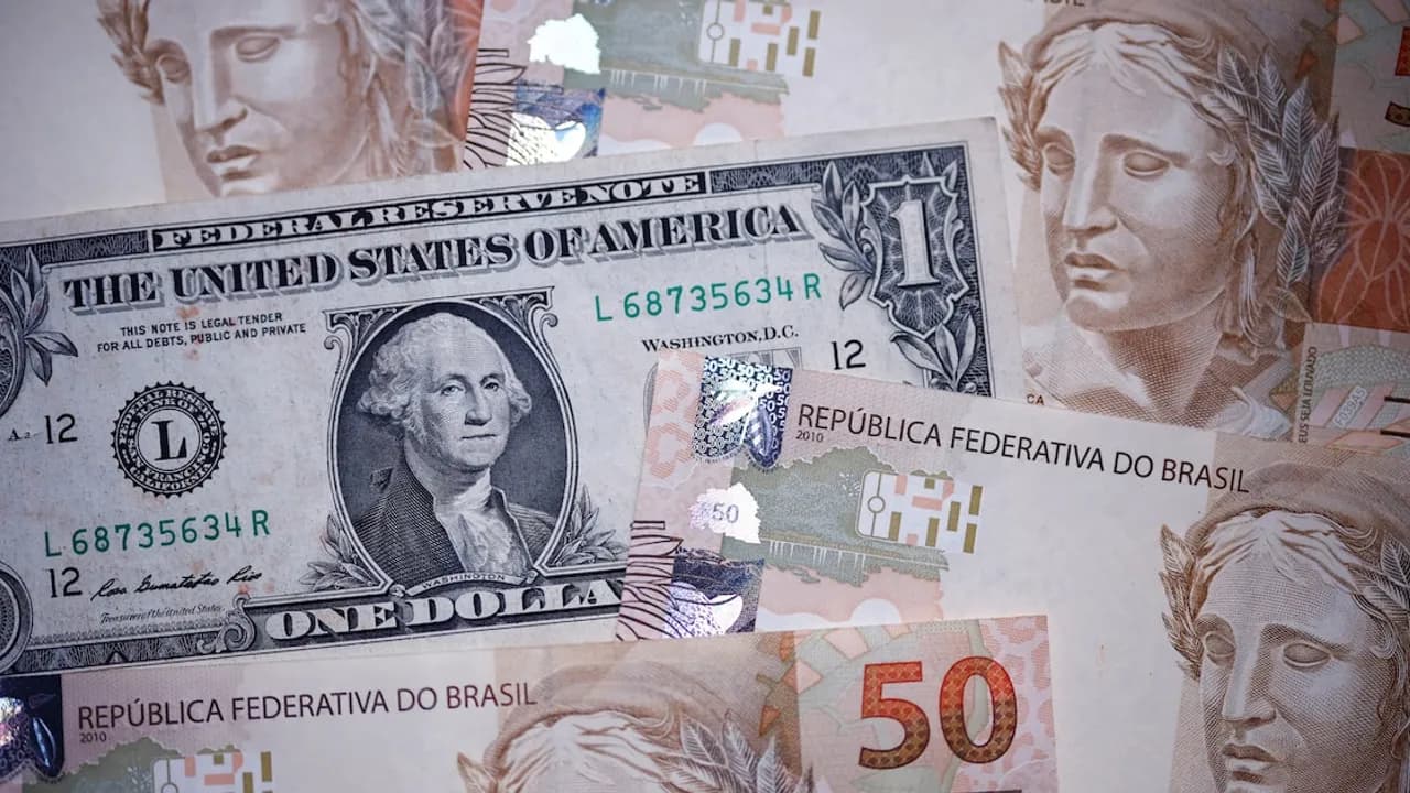 Billetes de cincuenta reales brasileños desplegados junto a un billete de un dólar estadounidense