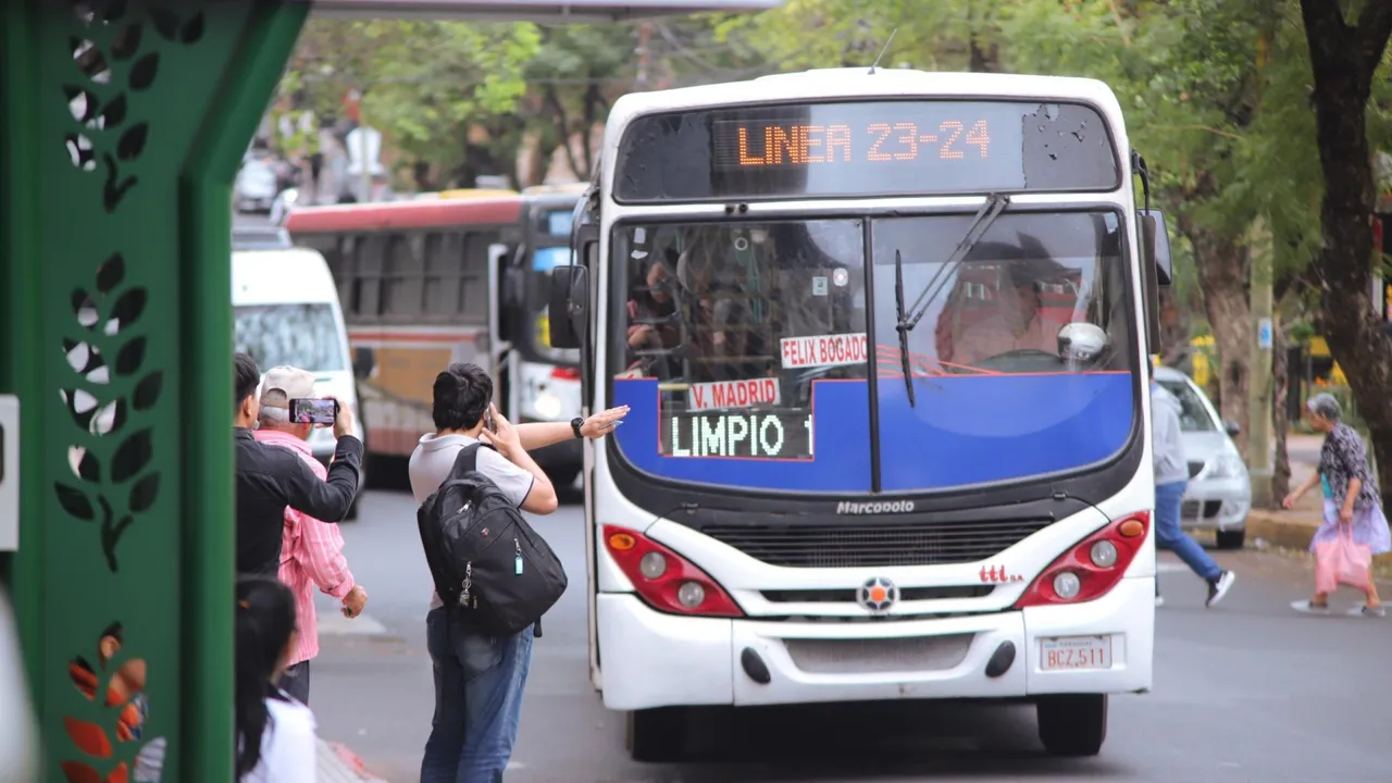 Colectivo de la línea 23 y 24 alzado de pasajeros en una parada urbana mientras una persona hace señas al conductor.