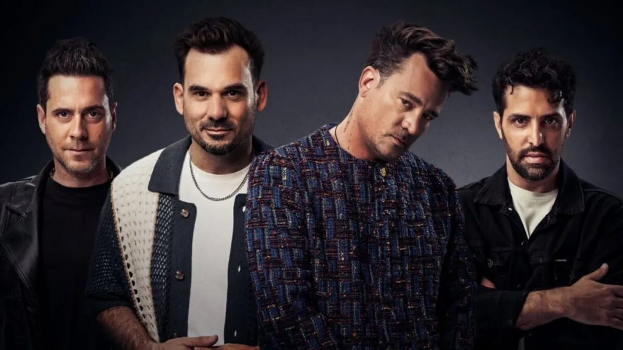 Cuatro integrantes de la banda de pop rock posan juntos frente a un fondo neutro mirando a cámara
