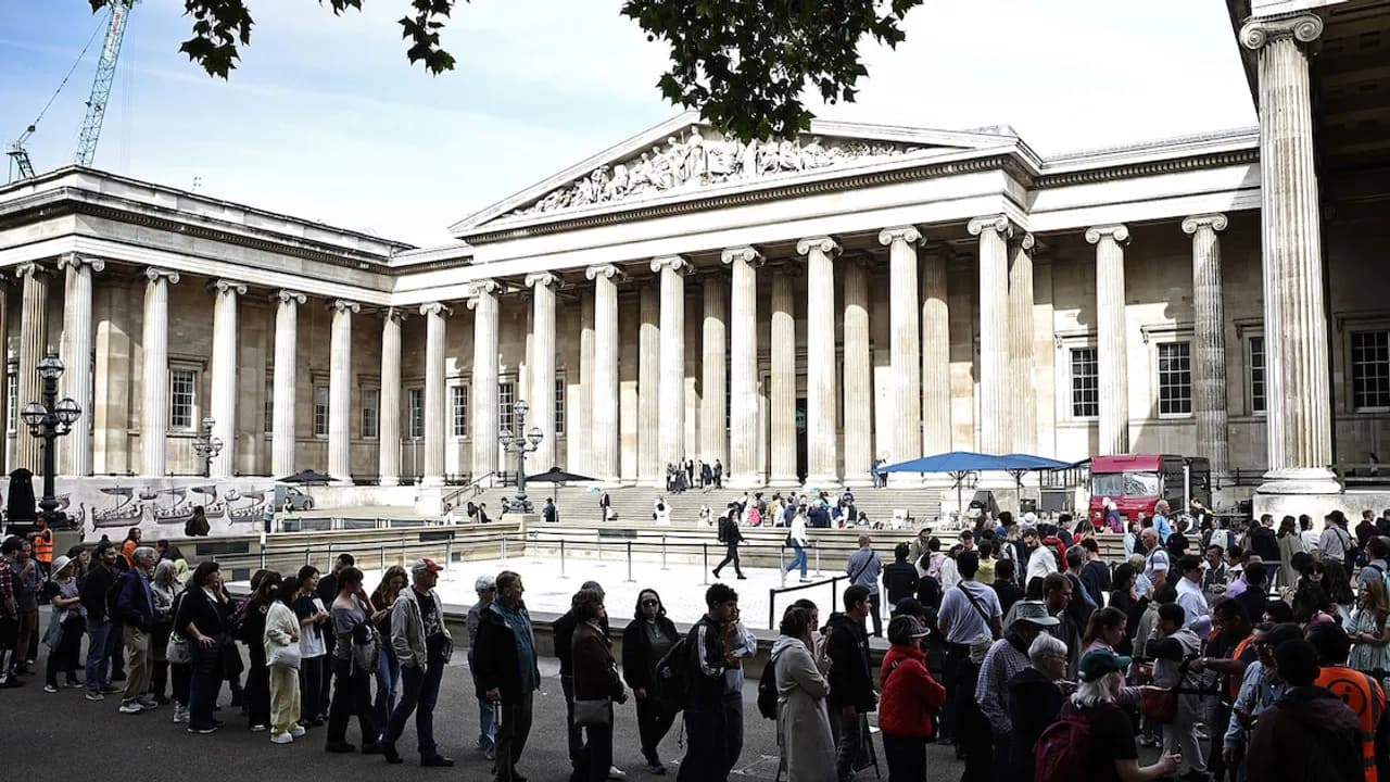 Personas forman una larga fila frente a la fachada de columnas clásicas de un edificio histórico durante el día.