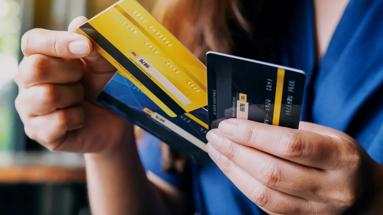 Manos de una persona sosteniendo varias tarjetas de crédito y débito de color amarillo, azul y negro.