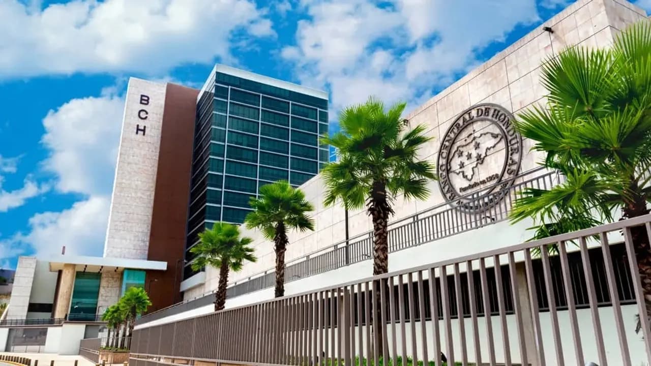 Fachada exterior del Banco Central de Honduras con su emblema oficial, palmeras y una verja perimetral.