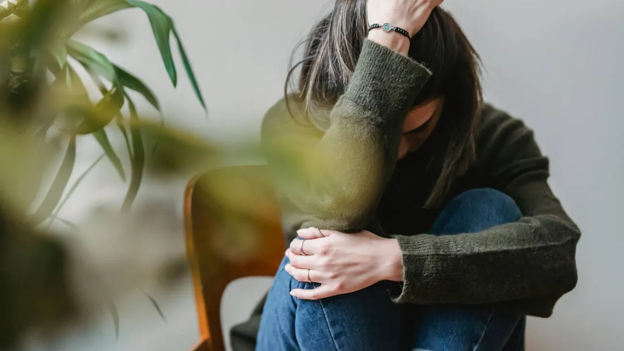 Mujer sentada en una silla con la cabeza inclinada y apoyada sobre su mano en actitud de preocupación o cansancio