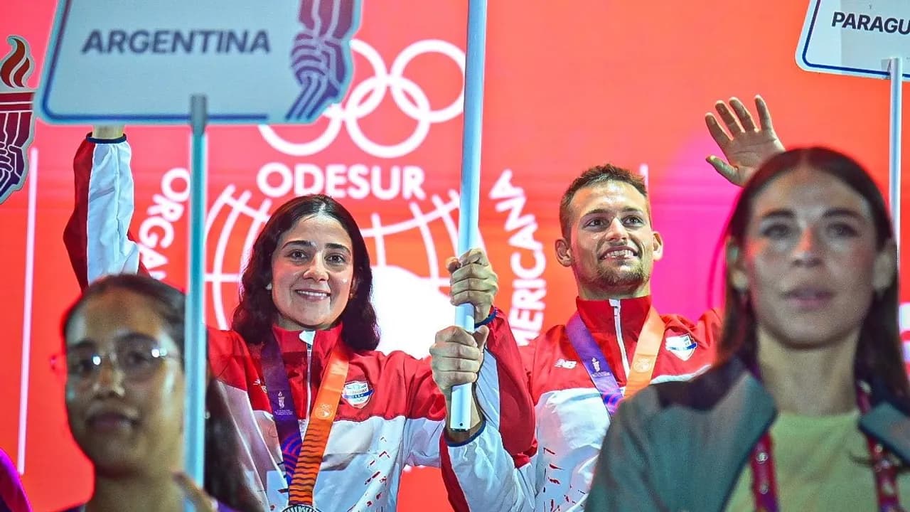 Atletas portan la bandera nacional y carteles alusivos durante la ceremonia de clausura de los juegos.
