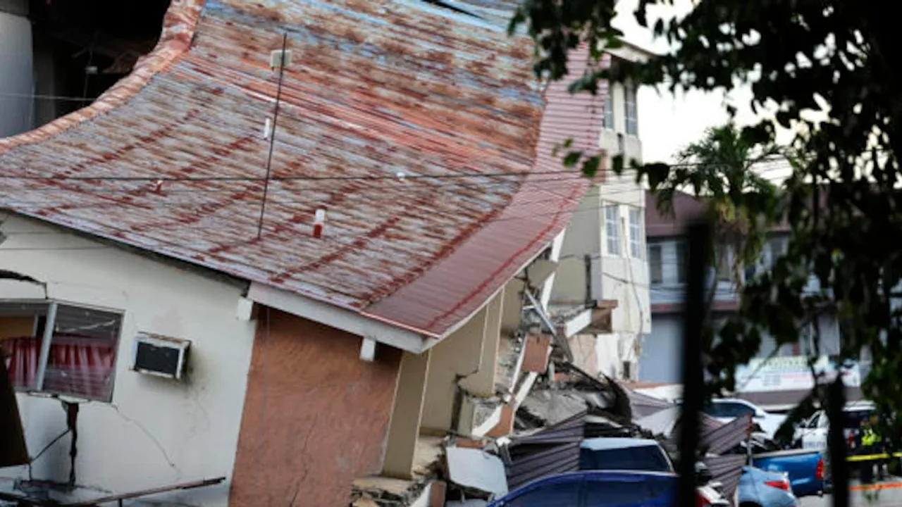 Edificio colapsado con el techo de chapa inclinado y escombros caídos sobre la calzada tras un sismo.