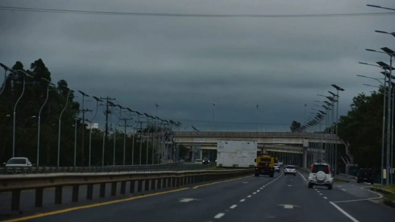 Autopista urbana bajo un cielo cubierto de nubarrones oscuros con vehículos circulando en Asunción.