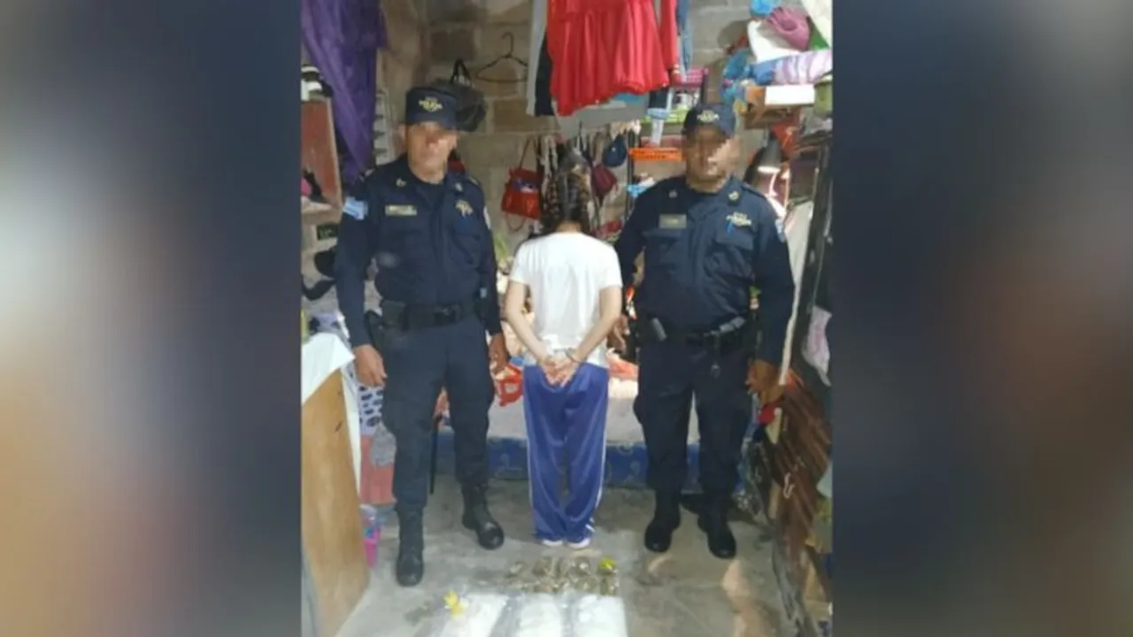 Dos agentes policiales custodian a una joven aprehendida de espaldas frente a paquetes de sustancias decomisadas.