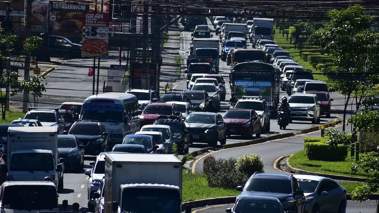 Fila densa de vehículos, autobuses y camiones en una concurrida avenida urbana durante una hora de tráfico intenso.
