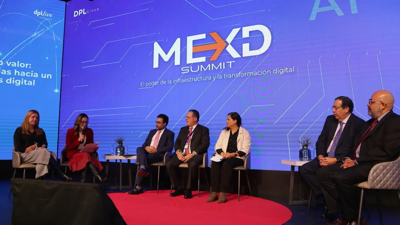 Panelistas debaten sentados en un escenario frente a una gran pantalla azul con el logotipo del congreso tecnológico.