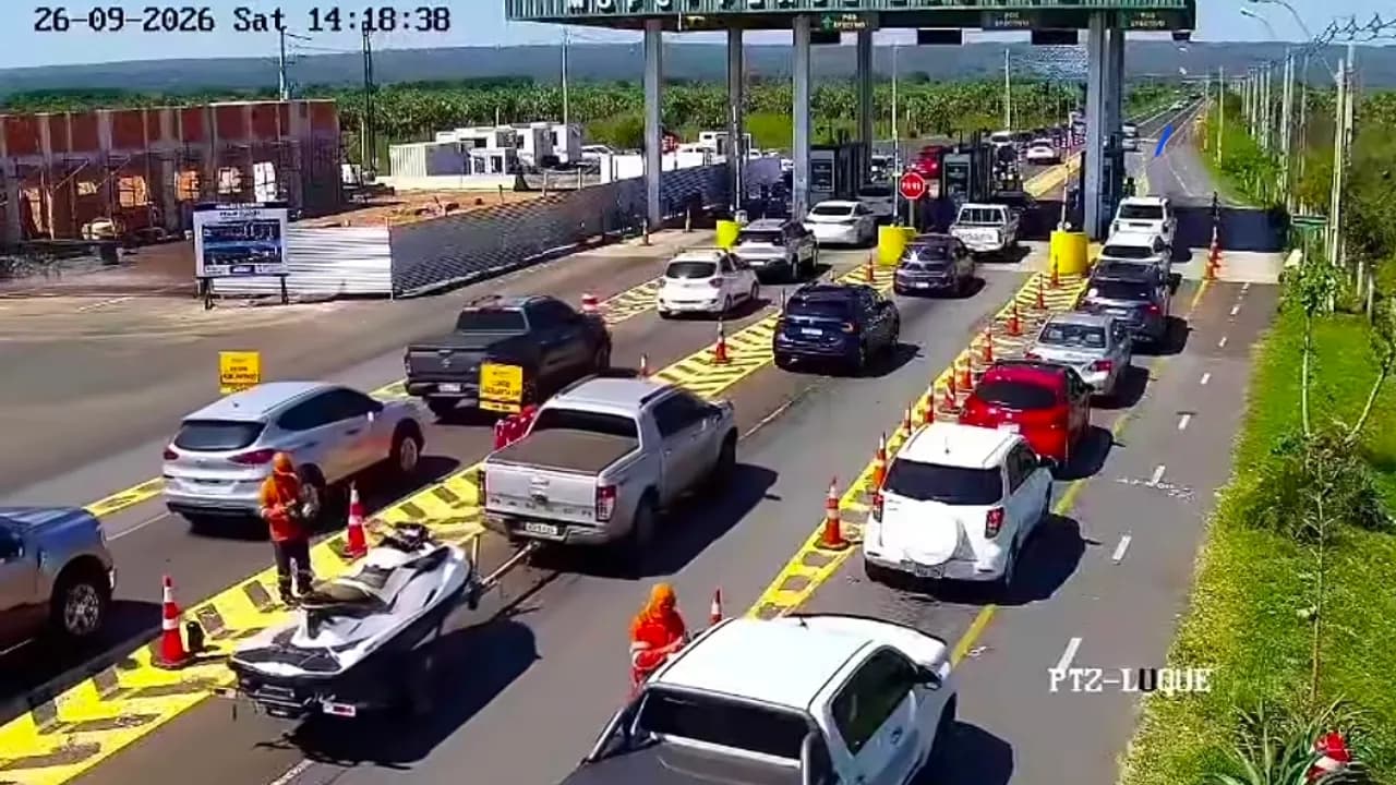 Fila de vehículos en el puesto de peaje con operarios cobrando la tarifa a los conductores sobre la ruta.