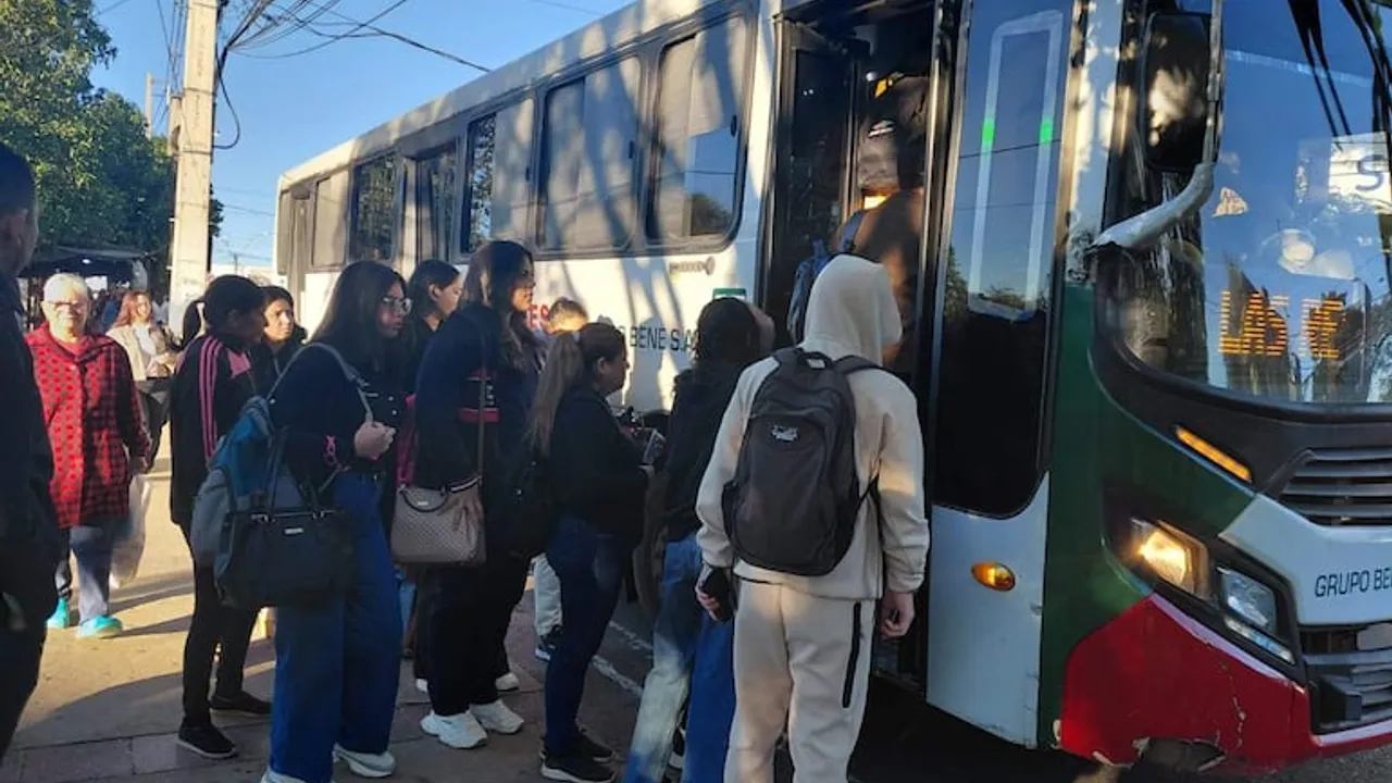 Pasajeros aguardan en fila para abordar un autobús de pasajeros en una parada de la vía pública durante el día