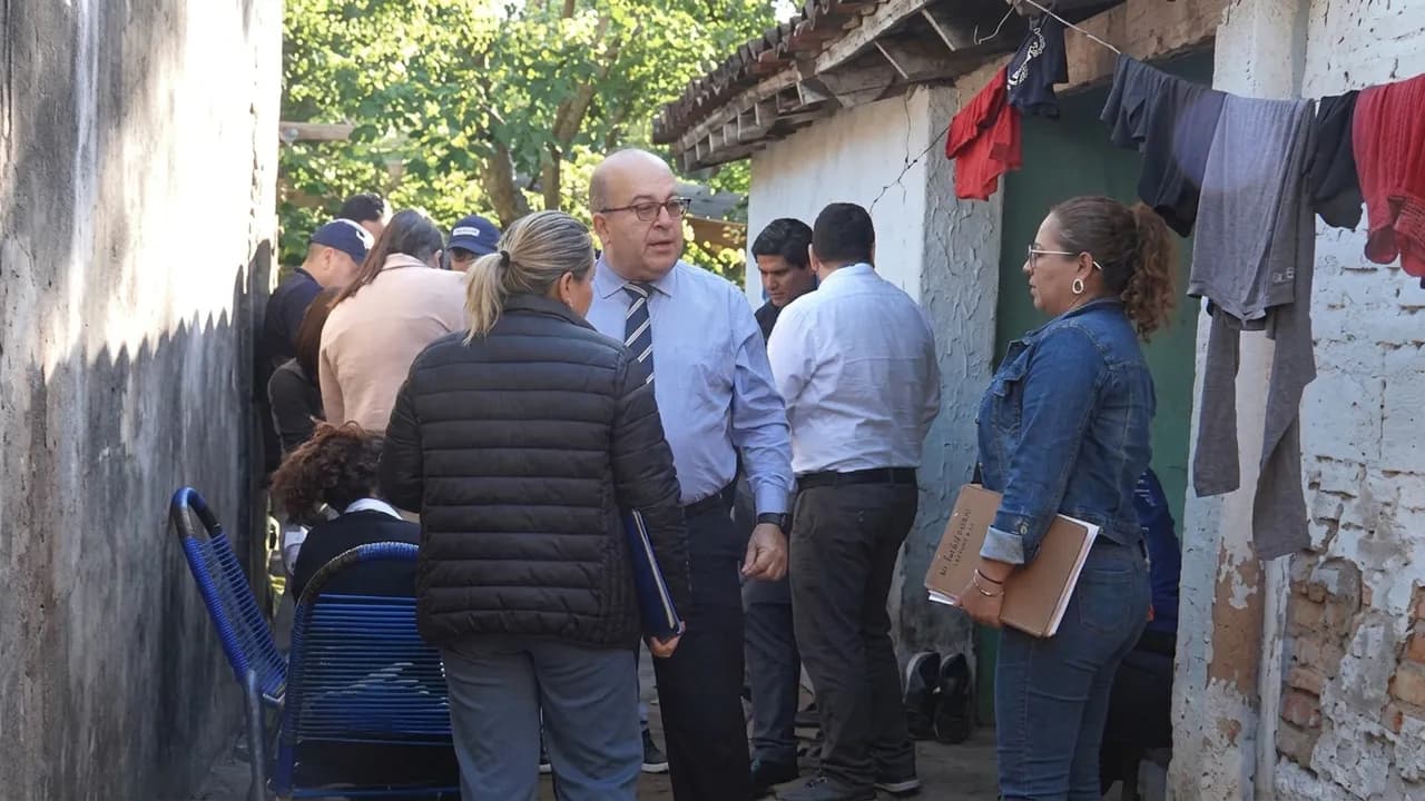 Agentes y comitiva fiscal conversan en el patio de una vivienda precaria durante un allanamiento.
