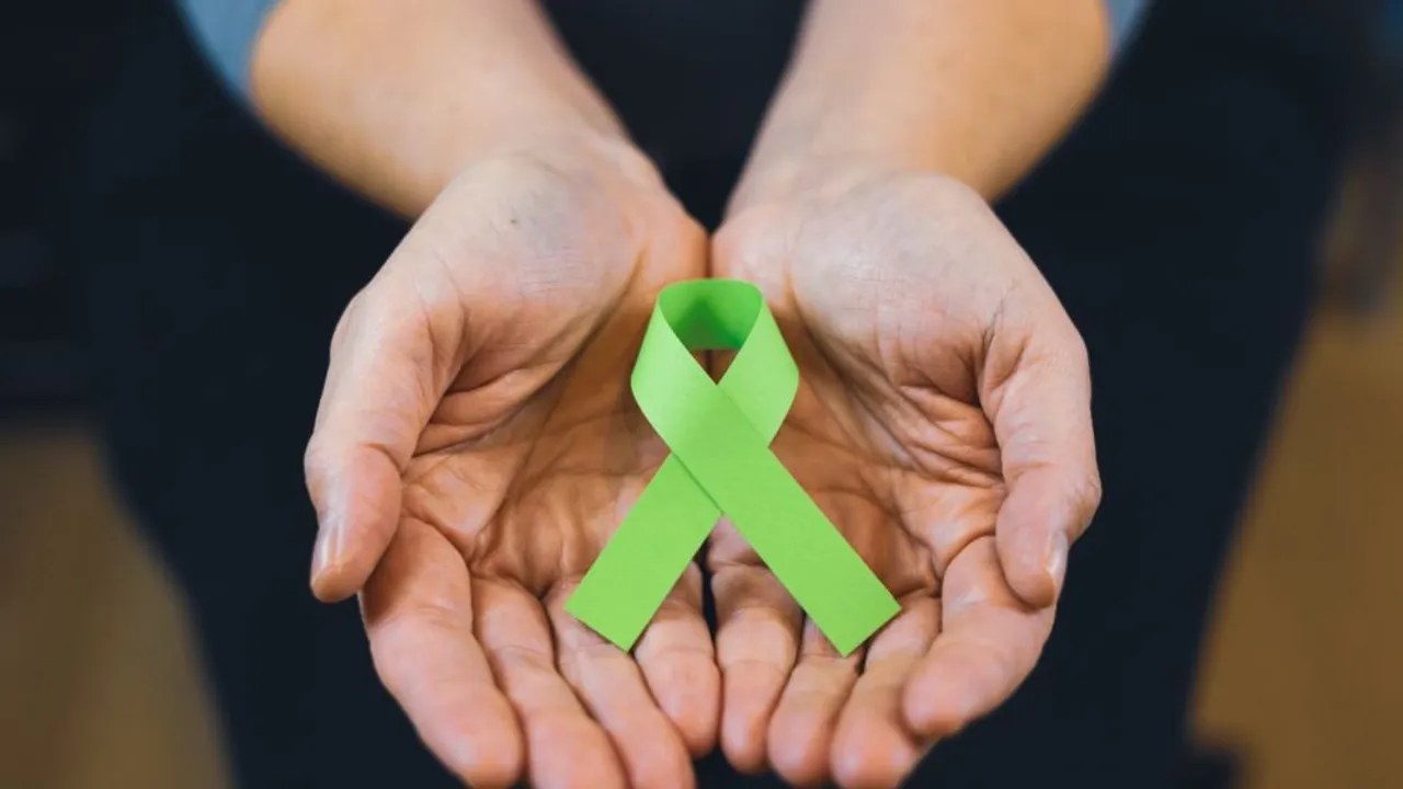 Manos abiertas sosteniendo una cinta de color verde claro, símbolo de la concienciación sobre el linfoma.