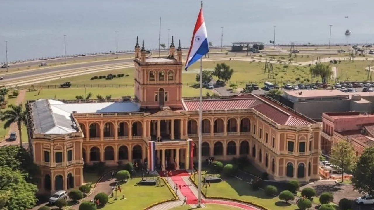 Fachada del Palacio de López en Asunción con la bandera paraguaya izada frente a la costanera y la bahía.