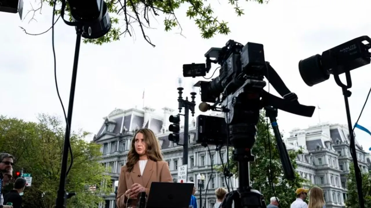Periodista con micrófono frente a cámaras de televisión en las inmediaciones del complejo de la Casa Blanca.