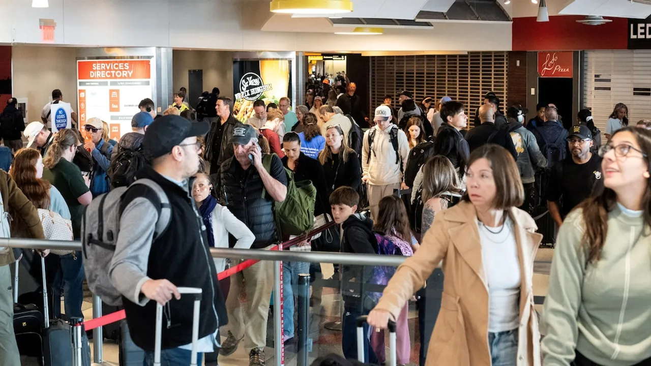 Pasajeros con equipaje hacen fila en el pasillo de una concurrida terminal de aeropuerto internacional.