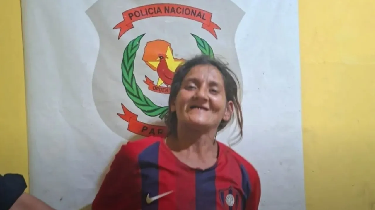 Mujer sonriendo con camiseta deportiva frente a un logotipo mural de la Policía Nacional de Paraguay.