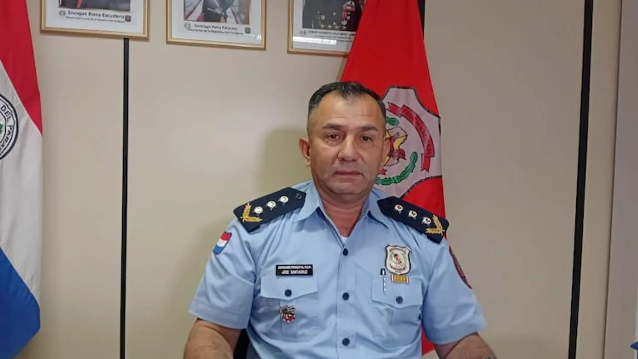 El comisario José Santacruz en su despacho policial con uniforme oficial junto a la bandera paraguaya.