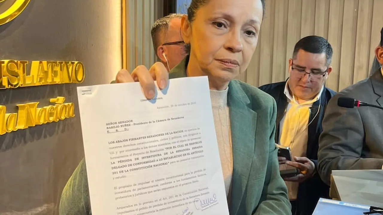 Mujer en traje verde sostiene una hoja impresa con un pedido de pérdida de investidura frente a periodistas